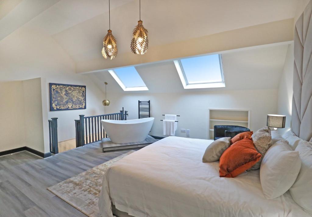 a bedroom with a large white bed and a tub at Black Pearl Stays - Saltburn Apartments in Saltburn-by-the-Sea