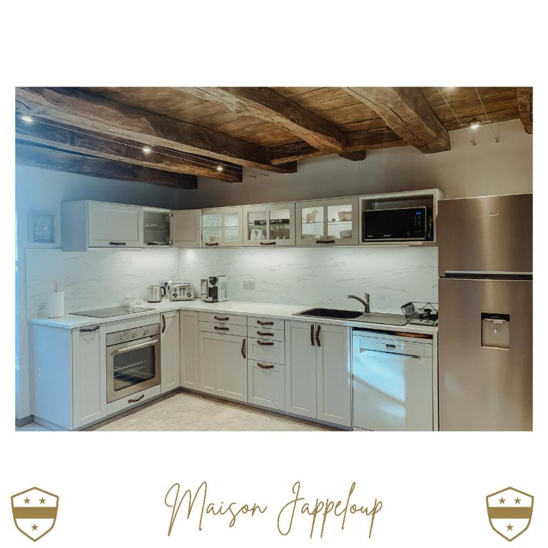 a kitchen with white cabinets and stainless steel appliances at Château de Laforest - Les Hébergements in Thizy-les-Bourgs