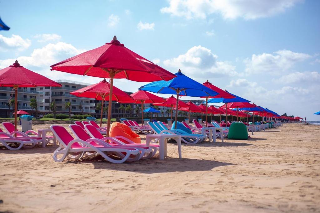 una fila de sillas y sombrillas en una playa en Porto Said Tourist Resort num3, en `Ezbet Shalabi el-Rûdi