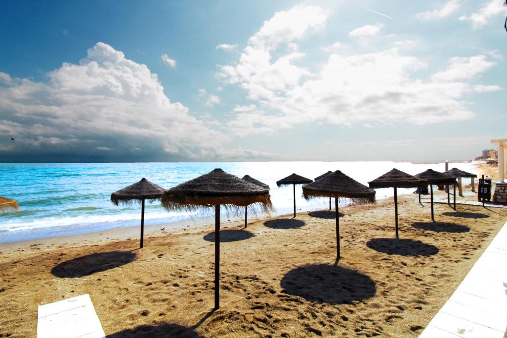 a row of umbrellas on a beach with the ocean at Yate 4, primera linea de playa. in Fuengirola