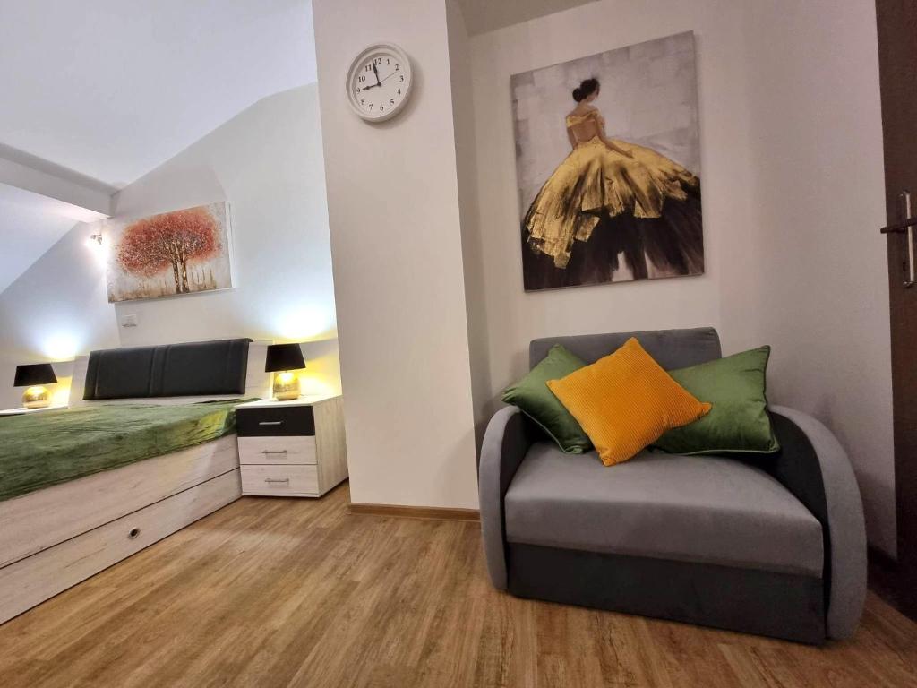 a living room with a couch and a clock on the wall at Byt v podkroví na Velkém náměstí in Hradec Králové
