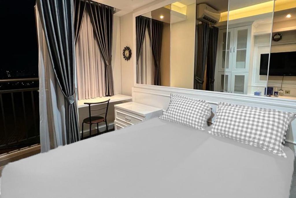 1 dormitorio con 1 cama blanca grande y espejo en RedLiving Apartemen Transpark Cibubur - Ens Room, en Depok