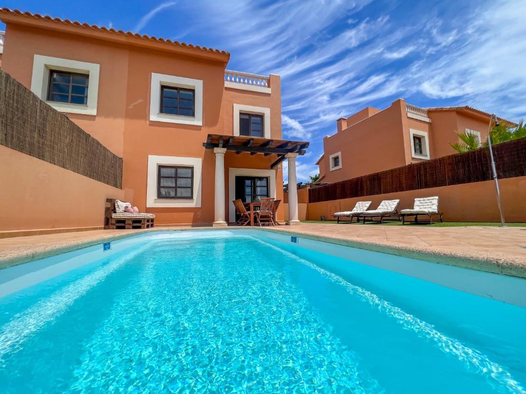 a swimming pool in front of a villa at Villa Tarabilla with private pool & ocean views in Corralejo