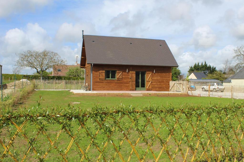 ein Holzhaus mit schwarzem Dach im Hof in der Unterkunft LE CHALET in Saint-Pierre-dʼArthéglise