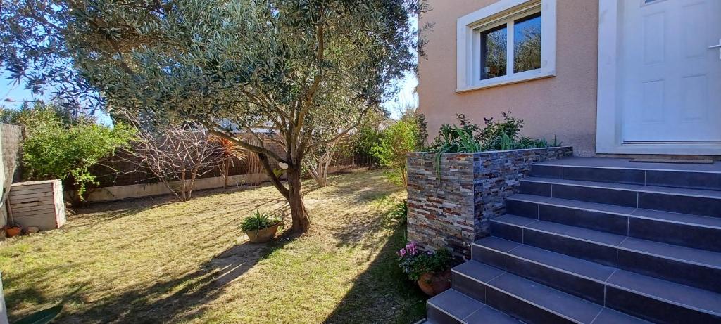 una casa con scale che conducono a un cortile con un albero di Villa climatisée avec piscine proche de la mer a Torreilles