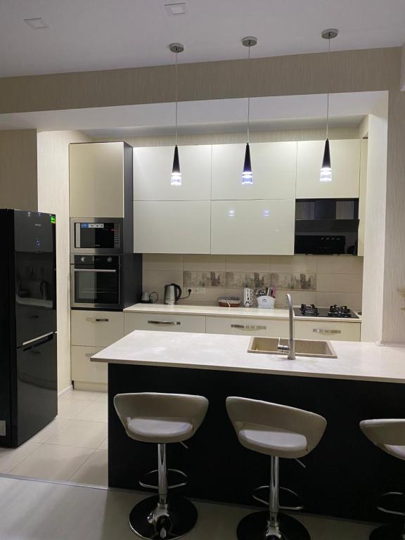 a kitchen with white cabinets and a sink and stools at Apartment Vake in Tbilisi City