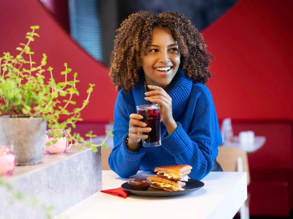 a woman sitting at a table with a glass of beer at ibis London Elstree Borehamwood in Borehamwood
