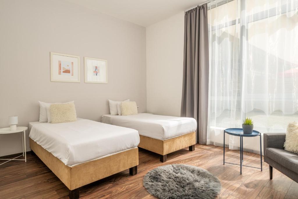 een slaapkamer met twee bedden en een bank en een raam bij Vagabond Downtown in Boedapest