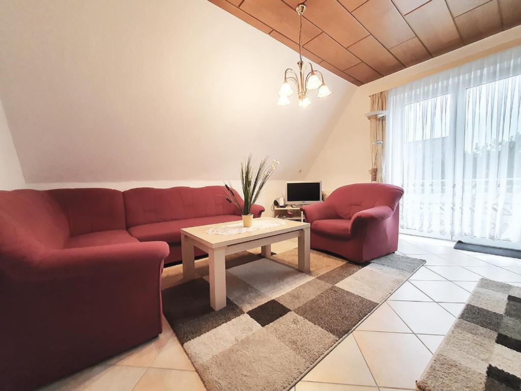 a living room with two red couches and a table at Friesenhain Ferienwohnungen in Sankt Peter-Ording