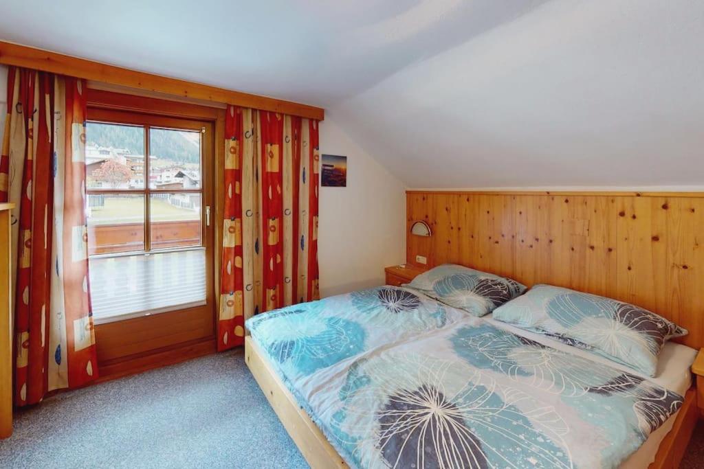 a bedroom with a bed and a large window at Julach Haus Apartment in Längenfeld