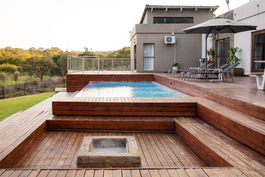 una piscina al aire libre con terraza y sombrilla en Elim Lakeside House, en Elim
