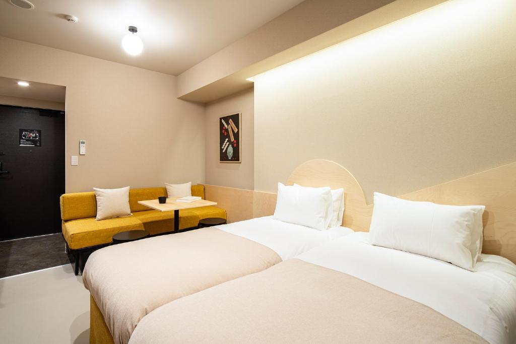 una habitación de hotel con 2 camas y una silla amarilla en Section L Yushima-Ueno, en Tokio