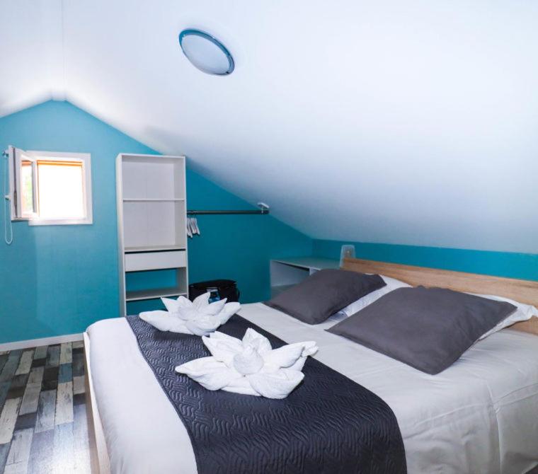 a bedroom with a bed with two white flowers on it at Village Drôles d&#39;Oiseaux in Le Teich