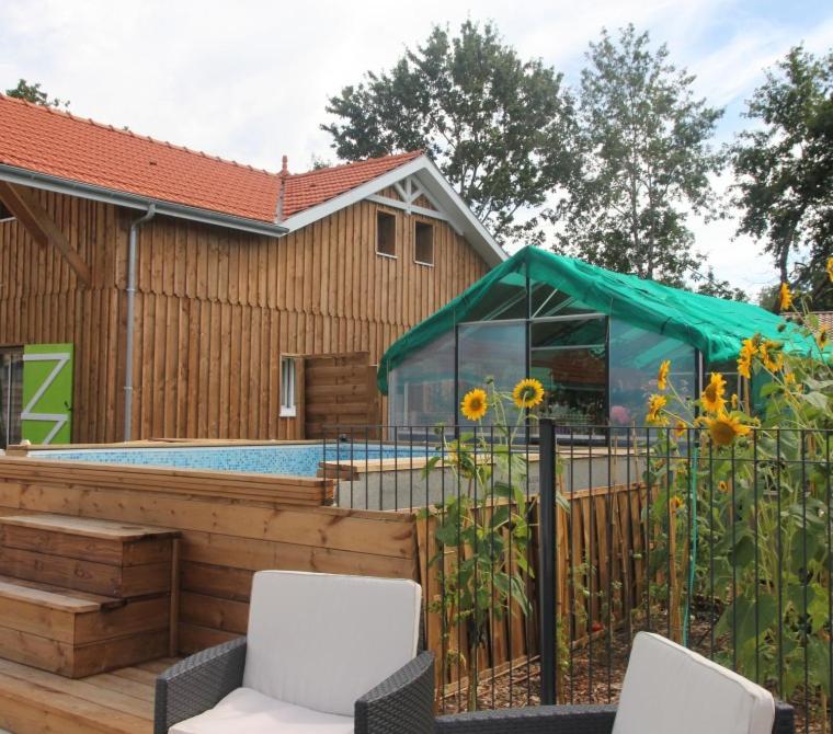 a patio with two chairs and a fence with sunflowers at Village Drôles d&#39;Oiseaux in Le Teich