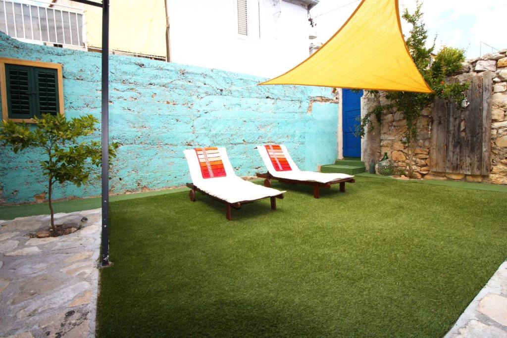 Authentic Stone House with an outdoor living room في يزيرا: كرسيان على عشب مع مظلة صفراء