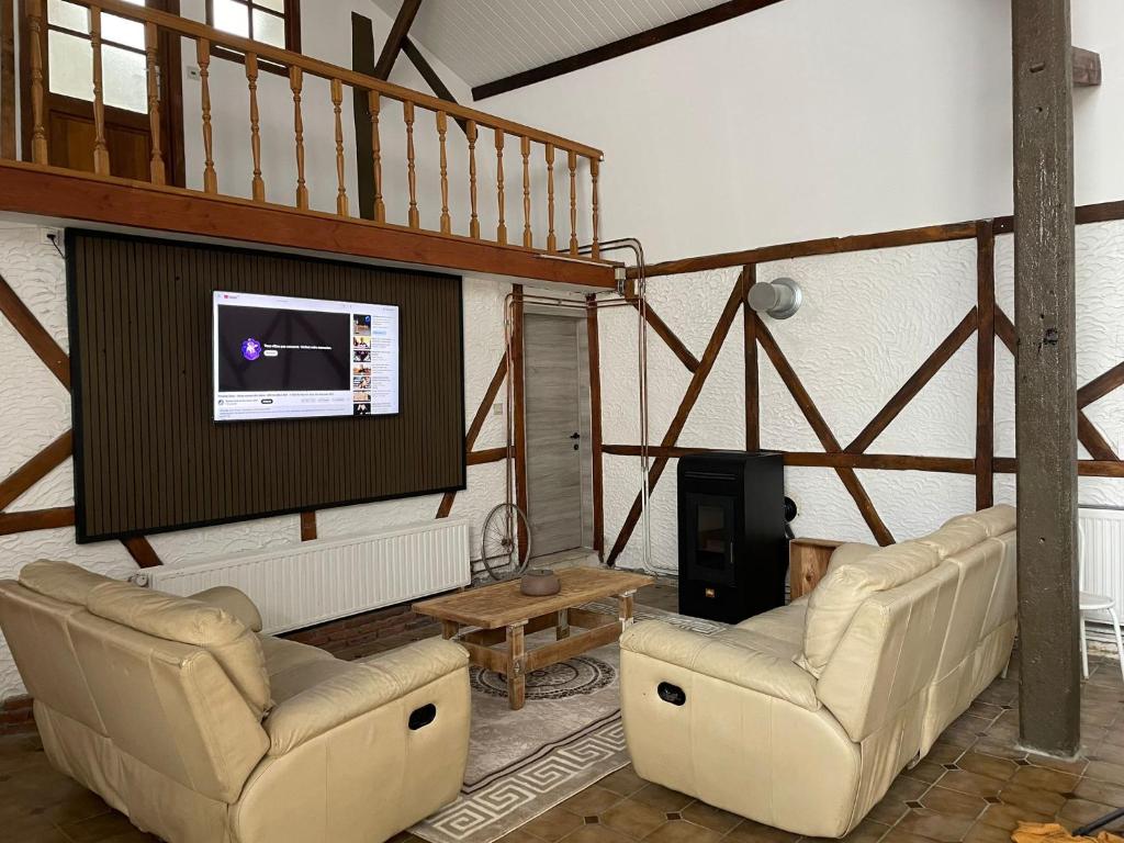 sala de estar con 2 sillas y TV de pantalla plana en La bergerie, en La Bruyère