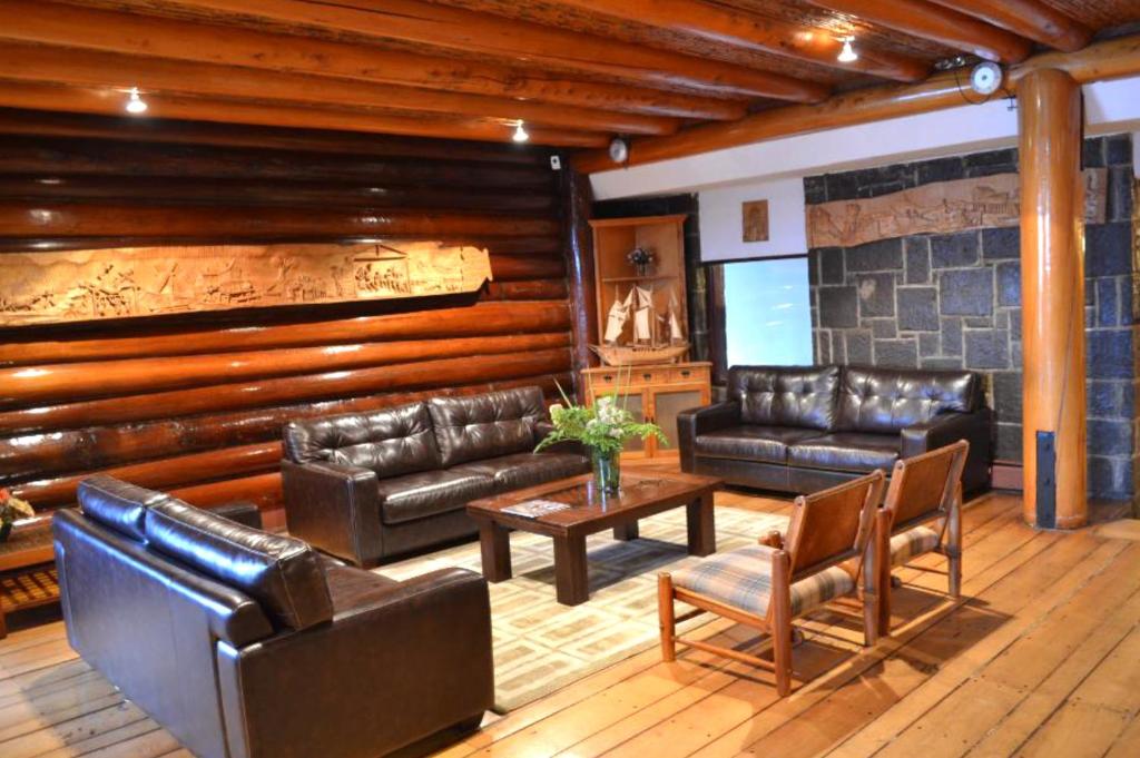 a living room with leather couches and a television at Panamericana Hotel Ancud in Ancud