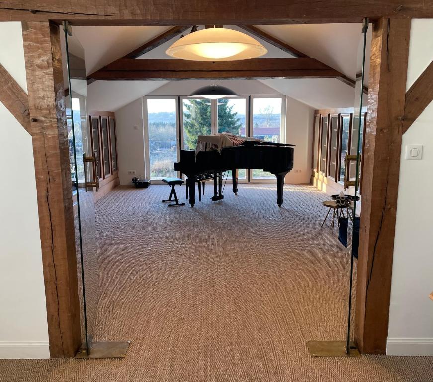una camera con pianoforte a coda in una stanza con finestre di Les Quartiers d'Annelise a Verdun-sur-Meuse