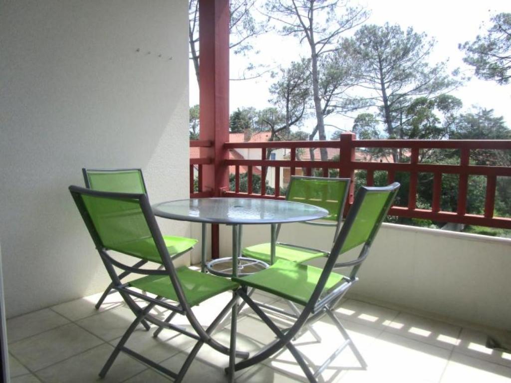 a glass table and four green chairs on a balcony at Appartement Capbreton, 3 pièces, 4 personnes - FR-1-239-453 in Capbreton