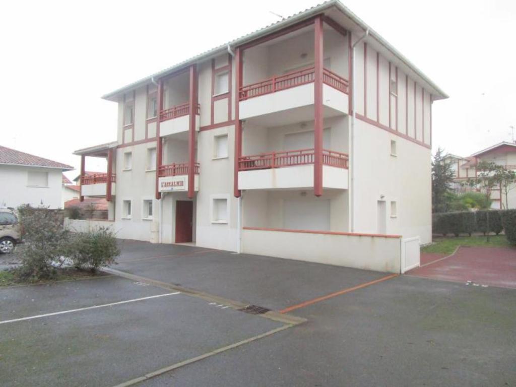 a large white building with red balconies in a parking lot at Appartement Capbreton, 3 pièces, 4 personnes - FR-1-239-453 in Capbreton
