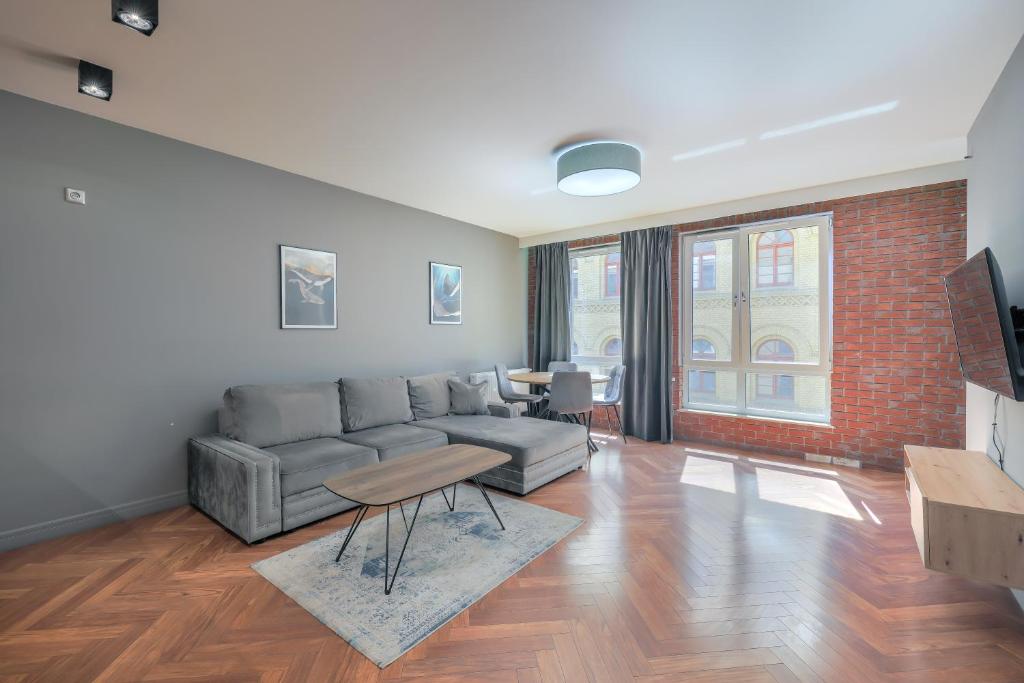 salon z szarą kanapą i ceglaną ścianą w obiekcie ApartMate- Perfect Apartment Oldtown Gdansk w Gdańsku