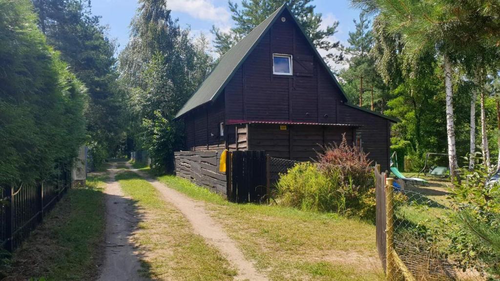 a barn with a dirt road next to a fence at domki nad jeziorem, las, do 10 osób jezioro Wilczyńskie Budzisławskie - domek letniskowy osobno ogrodzony, ogrzewany - wielkopolska, 62-550 Zygmuntowo gm Wilczyn in Zygmuntowo