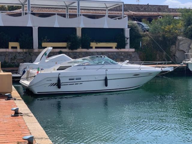 a white boat sitting in the water next to a dock at Bed & Boat Porto Rotondo in Marinella