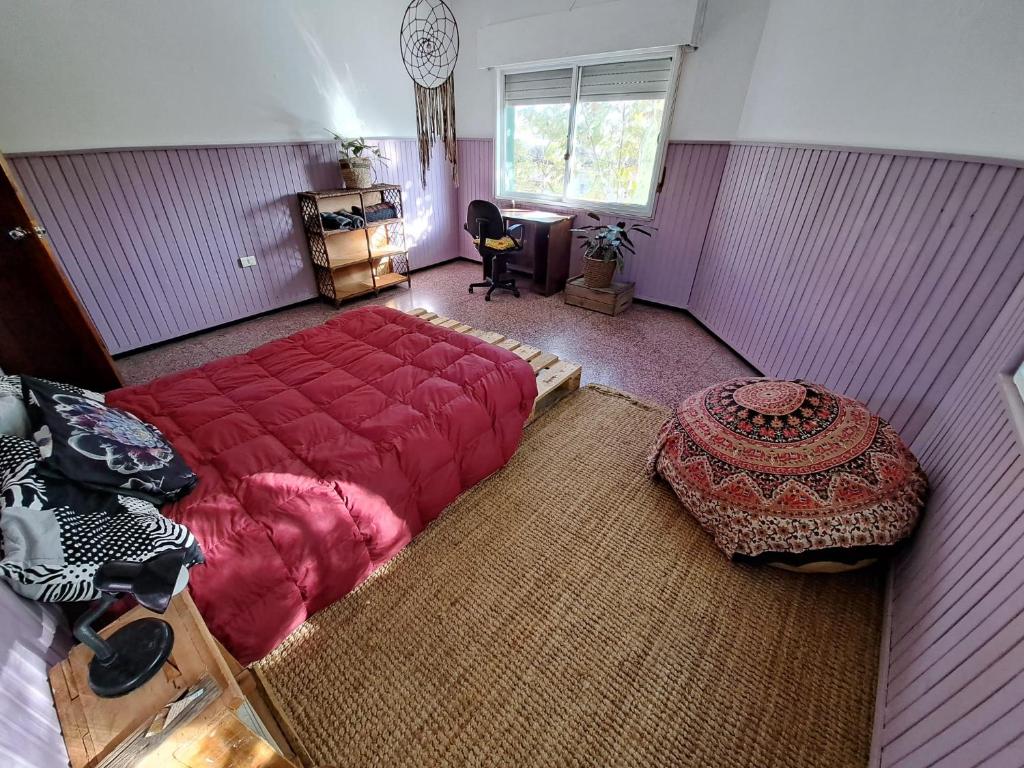 Un dormitorio con una gran cama roja y una mesa en Casa Agni, en Treinta y Tres