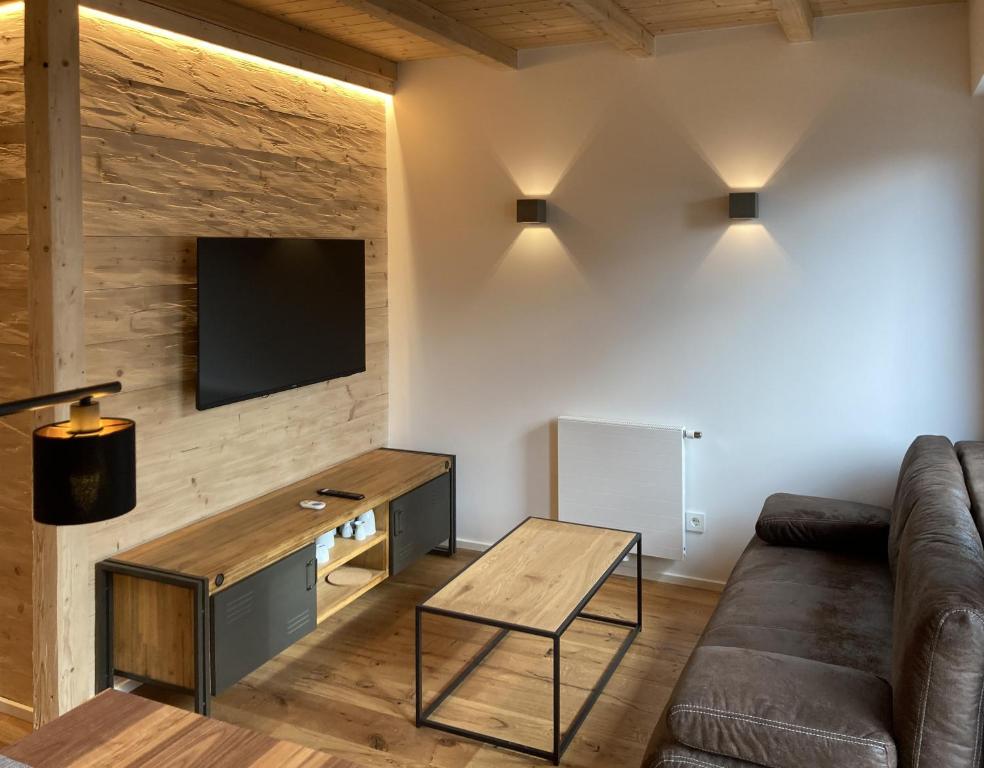 a living room with a couch and a tv on a wall at Filder-Appartements in Filderstadt