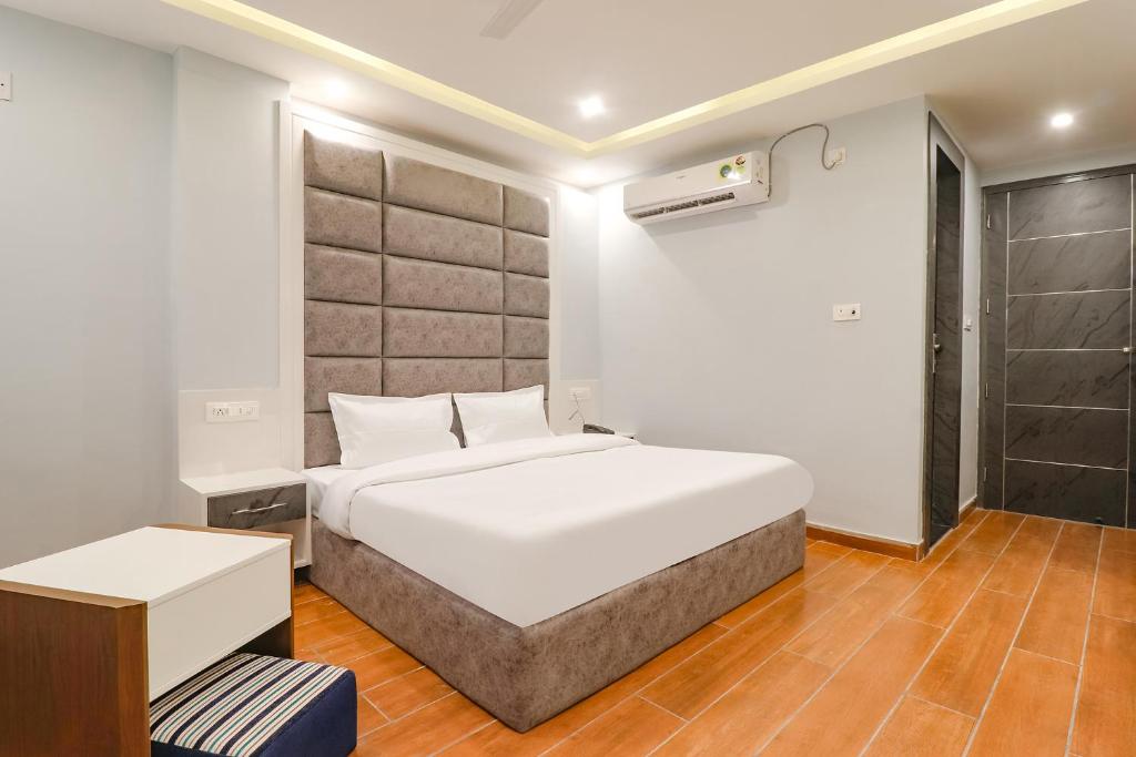 um quarto com uma grande cama branca e uma secretária em FabHotel Av Royale em Dehradun