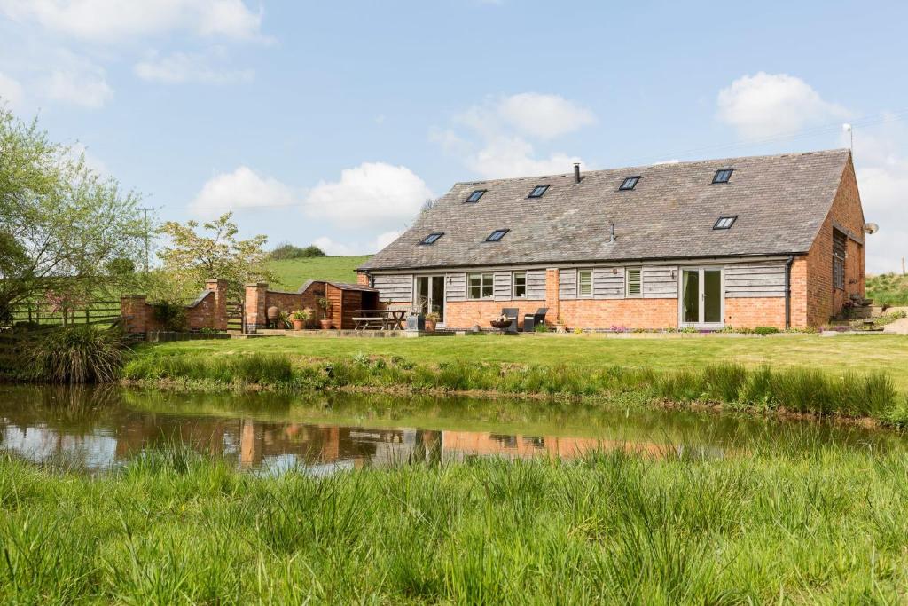 una antigua casa de campo con un estanque delante en Chater Barn en Leicester