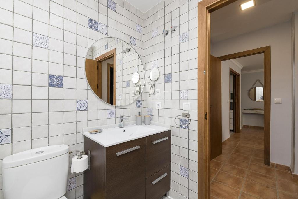 łazienka z toaletą, umywalką i lustrem w obiekcie Rincon de los Deseos w mieście Benamahoma