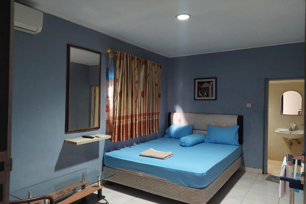 Schlafzimmer mit blauen Wänden und einem Bett mit Spiegel in der Unterkunft Pondok Seruni Kemanggisan Jakarta in Jakarta