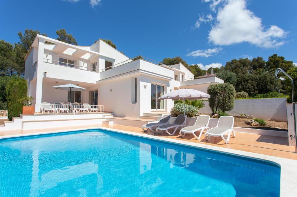 a villa with a swimming pool in front of a house at Villa Ermita by Sonne Villas in Cala Galdana