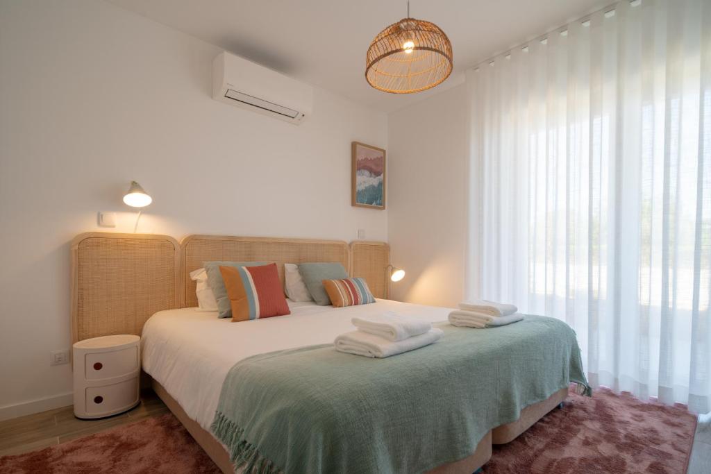 a bedroom with a bed with towels on it at Casa Cabanas - Cabanas Gardens in Cabanas de Tavira