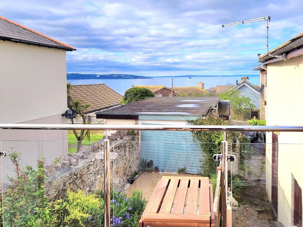 a view from the balcony of a house with a wooden bench at Honeysuckle Bay Cottage in Brixham