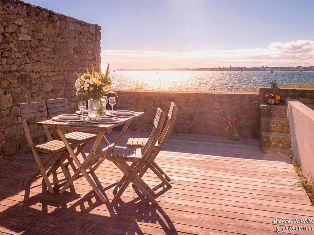 a wooden table and chairs on a deck with a view of the water at Maisonnette avec accès plage direct, 4/5 couchages, wifi - Gâvres - FR-1-349-117 in Gâvres