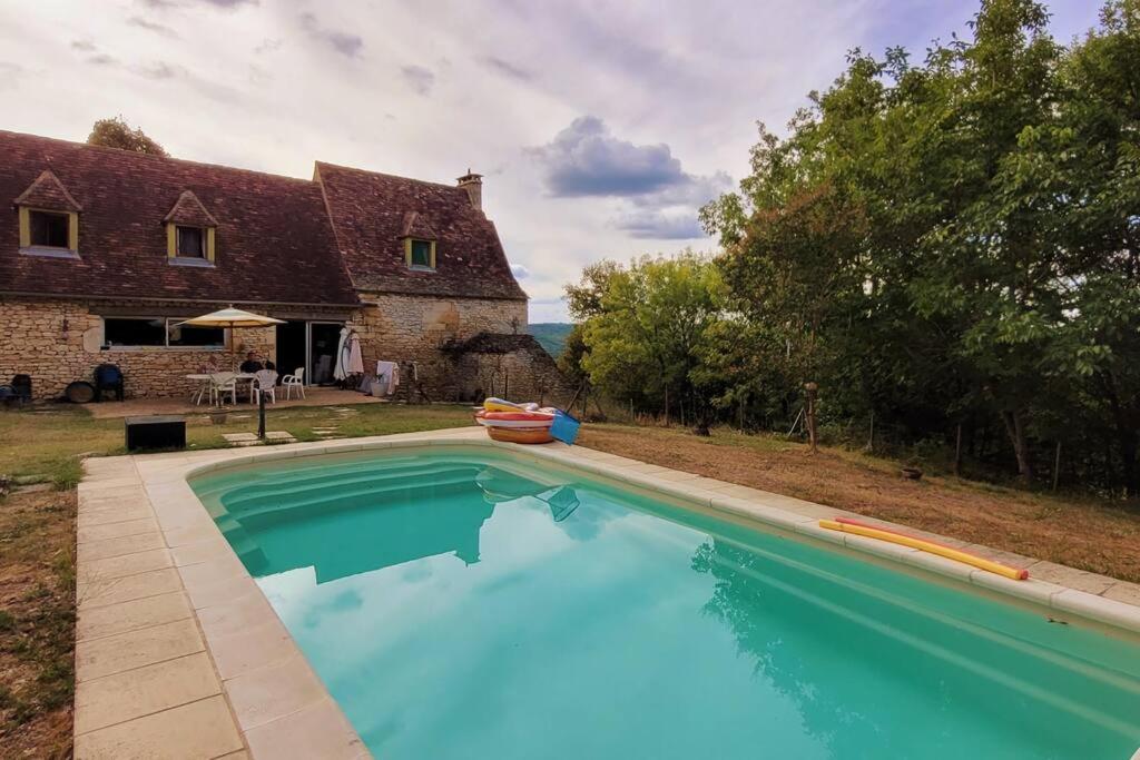 a large swimming pool in front of a house at Maison périgourdine avec vue et piscine chauffée in Peyzac-le-Moustier