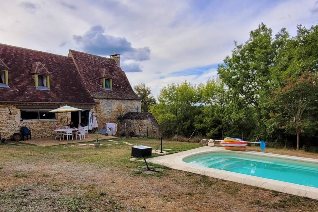 an old stone house with a swimming pool in front of it at Maison périgourdine avec vue et piscine chauffée in Peyzac-le-Moustier