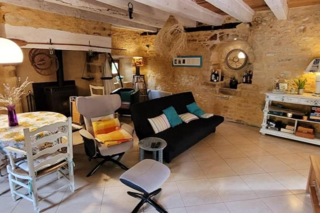a living room with a black couch and chairs at Maison périgourdine avec vue et piscine chauffée in Peyzac-le-Moustier