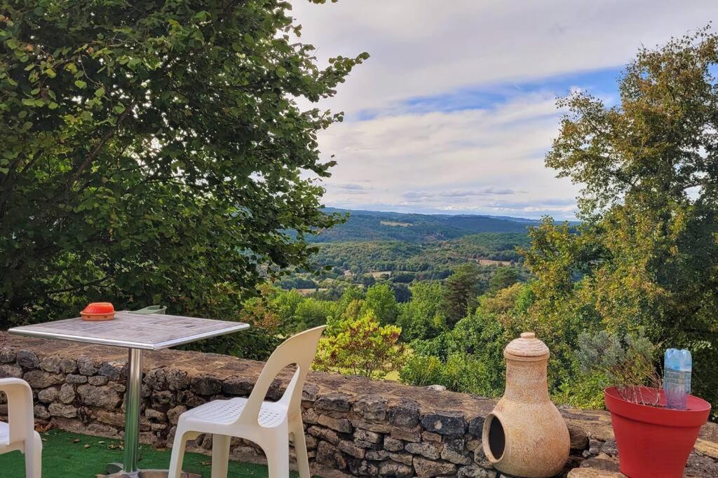 a table and chairs on a stone wall with a view at Maison périgourdine avec vue et piscine chauffée in Peyzac-le-Moustier