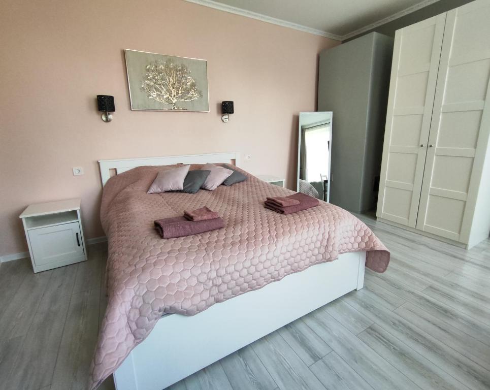 una camera da letto con un grande letto con lenzuola e cuscini rosa di Mezrozes a Ventspils