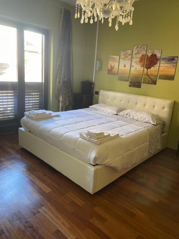 un grande letto bianco in una camera da letto con lampadario a braccio di Casa Di Marzio a Pratola Peligna