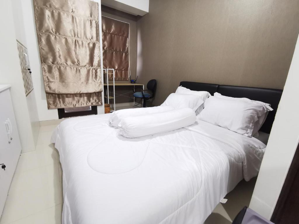 Bett mit weißer Bettwäsche und Kissen in einem Zimmer in der Unterkunft ARSAKHA 004 Transpark Cibubur By Nigiri Amour in Kalimanggis