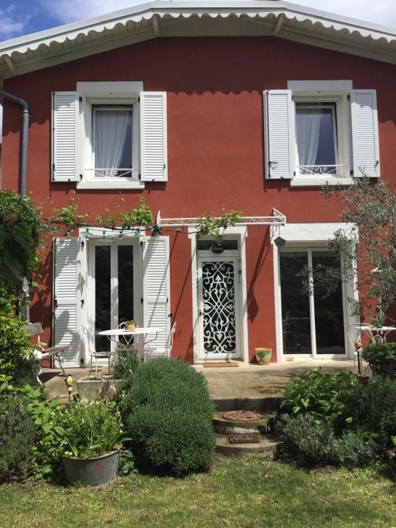 a red house with white windows and a porch at chambre pour 2 personnes in Sablons