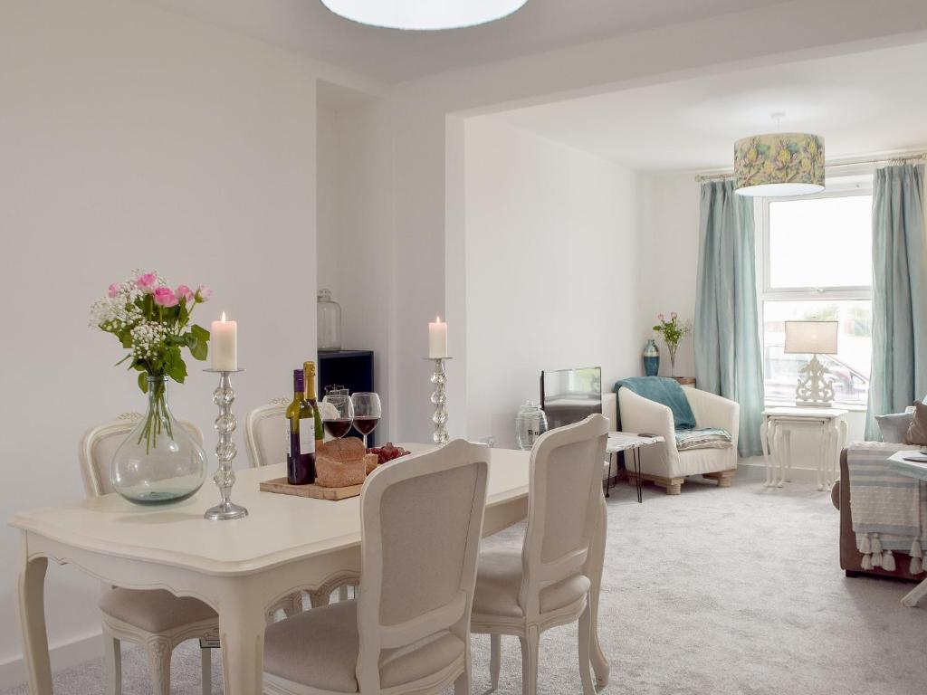 a white dining room with a table and chairs at Bwthyn Cerrigos in Milford Haven