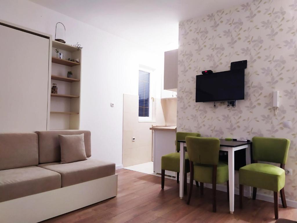 ein Wohnzimmer mit einem Sofa und einem Tisch mit grünen Stühlen in der Unterkunft Studio Petlja - Igalo in Herceg-Novi
