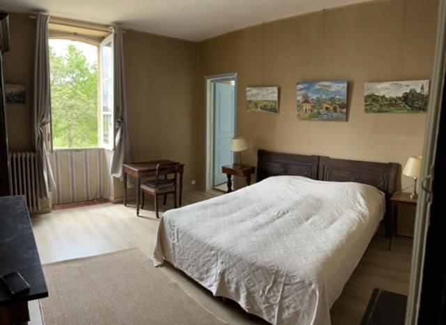 a bedroom with a bed and a desk and a window at Domaine de Rébert in Monguillem
