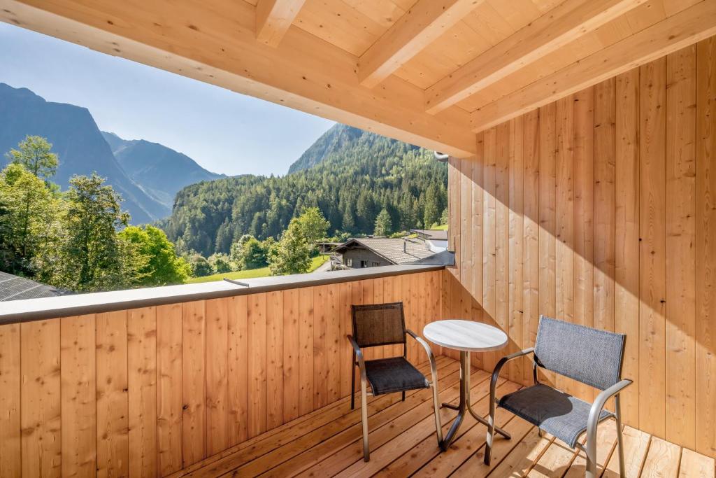 a room with a table and chairs on a balcony with mountains at Seehüter's Hotel Seerose - Piburger See, Ötz in Oetz