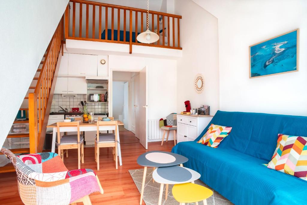 - un salon avec un canapé bleu et une table dans l'établissement Bananec- Appt à 300 mètres de la plage, à La Forêt-Fouesnant